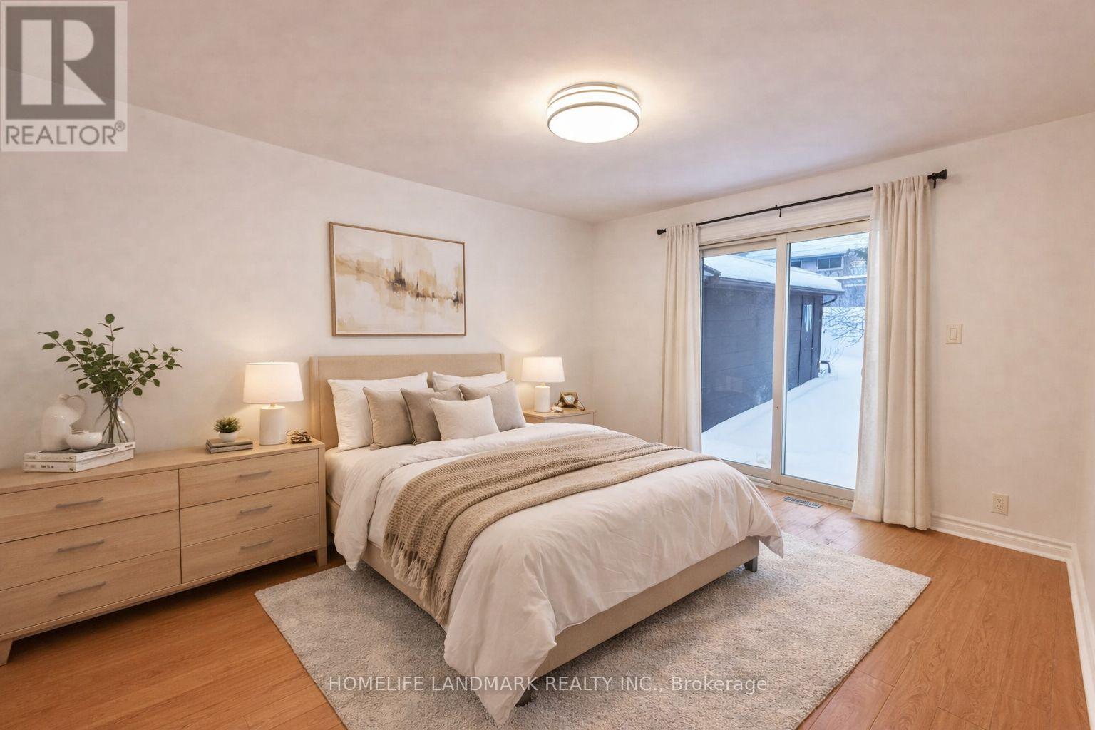 A well-lit bedroom with a large bed and a painting on the wall.