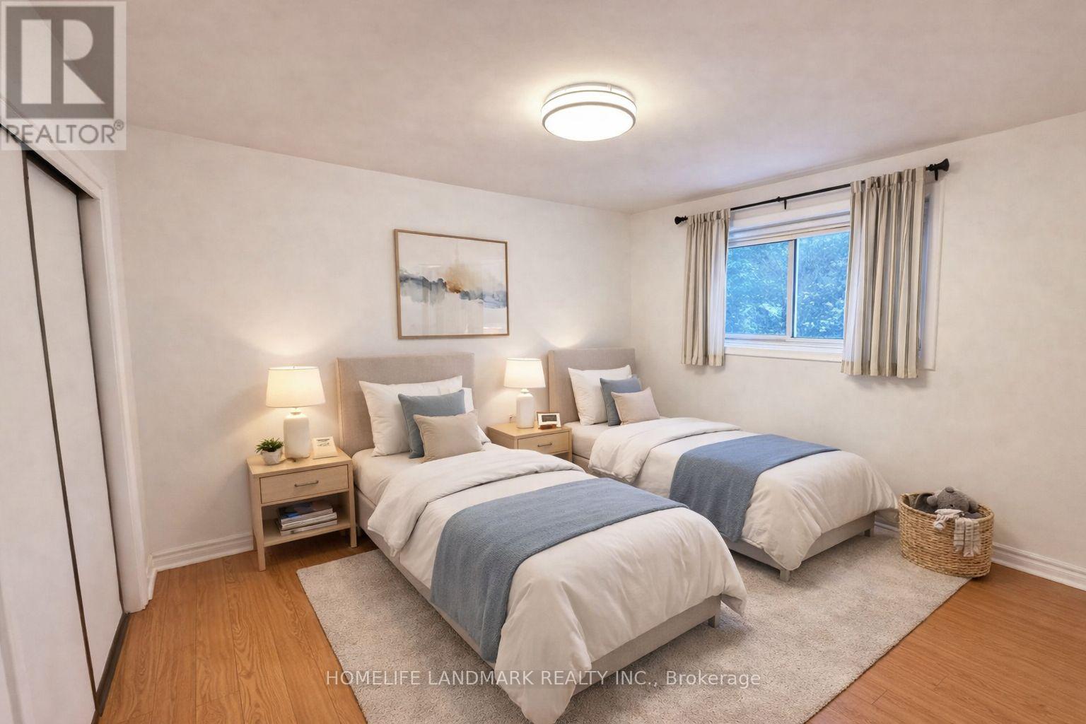 A bedroom with two beds and a nightstand with a lamp.