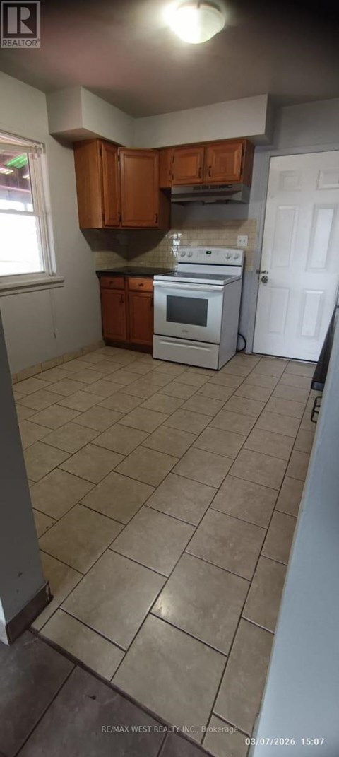 A kitchen with a white stove top oven and brown cabinets.