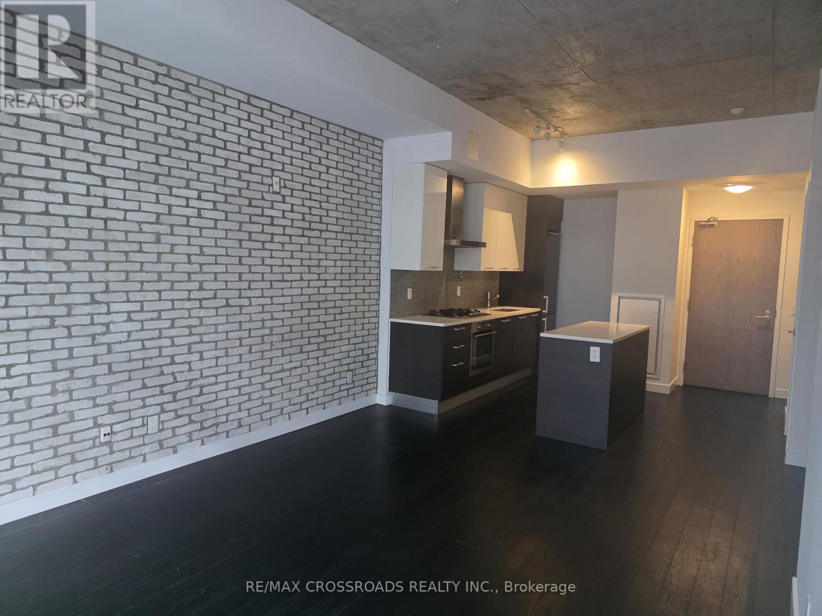 A kitchen with a brick wall and wooden floors.