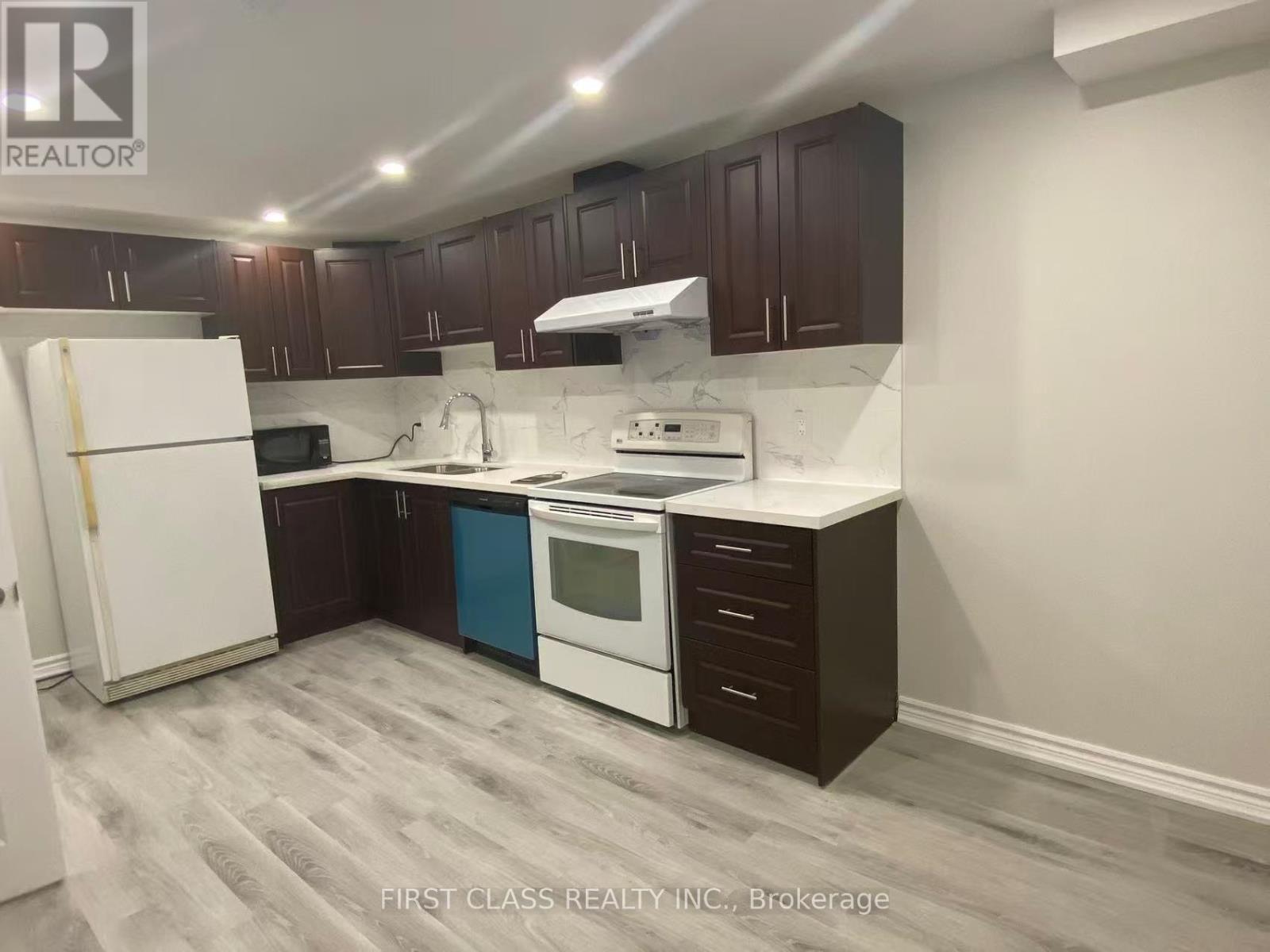 A kitchen with a white fridge, white countertops, and brown cabinets.