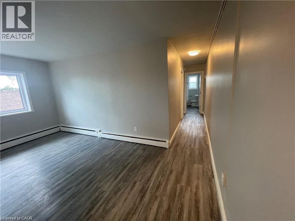 A long hallway with wood flooring and white walls.