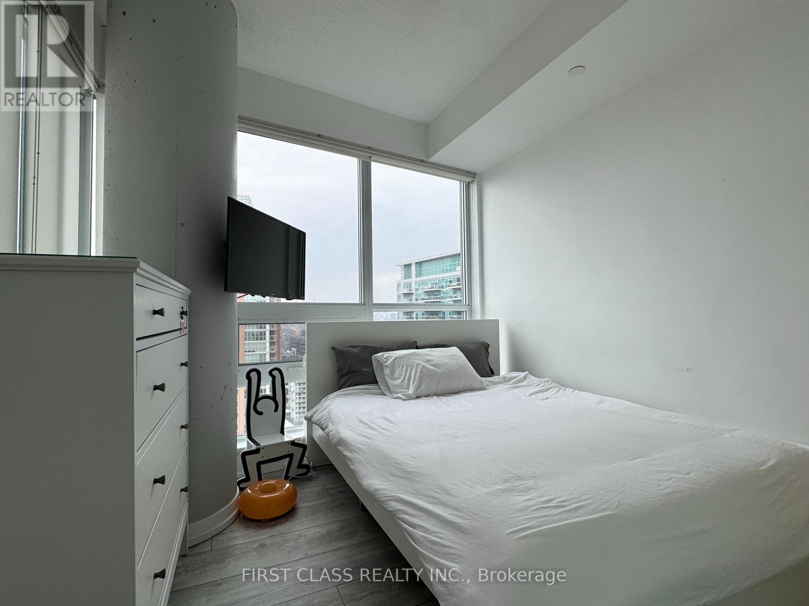 A bedroom with a bed, a television, and a window.