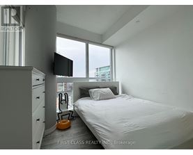 A bedroom with a bed, a television, and a window.