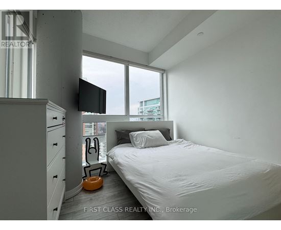 A bedroom with a bed, a television, and a window.