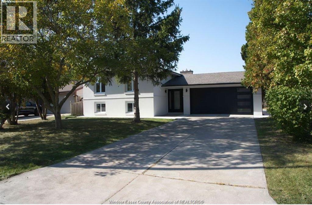 A house with a driveway and trees in front of it.