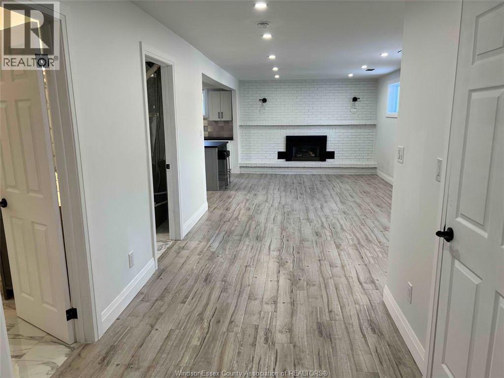 A spacious room with a fireplace and wood flooring.