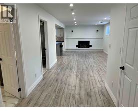 A spacious room with a fireplace and wood flooring.