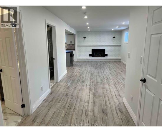 A spacious room with a fireplace and wood flooring.