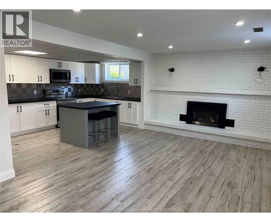 A kitchen with a white fireplace and wooden floors.