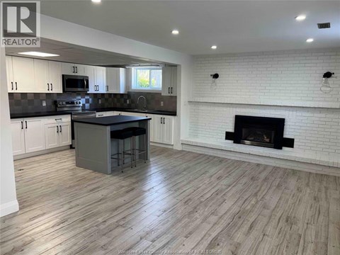 A kitchen with a white fireplace and wooden floors.