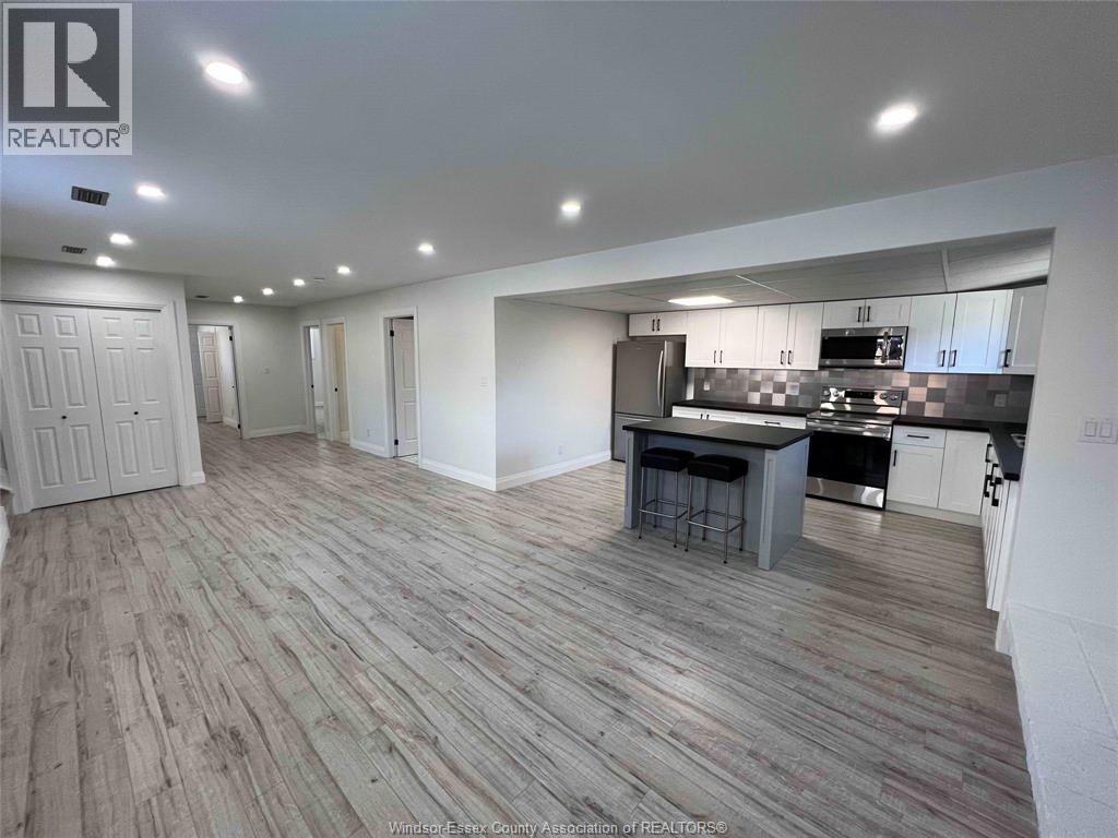 A spacious kitchen and dining area with wooden flooring and white walls.