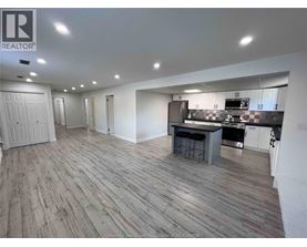 A spacious kitchen and dining area with wooden flooring and white walls.