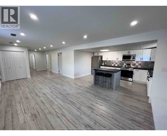 A spacious kitchen and dining area with wooden flooring and white walls.