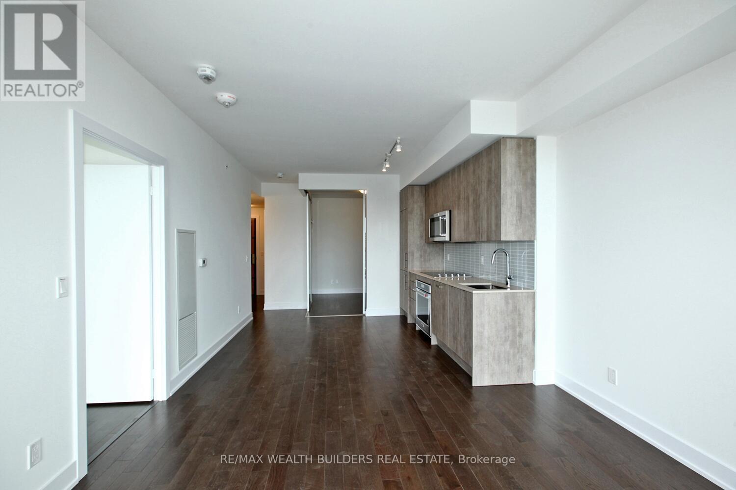 A spacious, empty room with wooden floors and white walls.