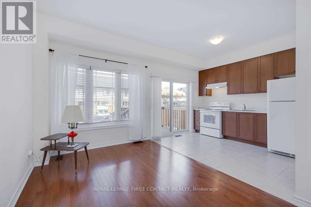 A well-lit, spacious kitchen and living room with wooden floors and white walls.
