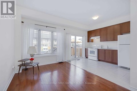 A well-lit, spacious kitchen and living room with wooden floors and white walls.
