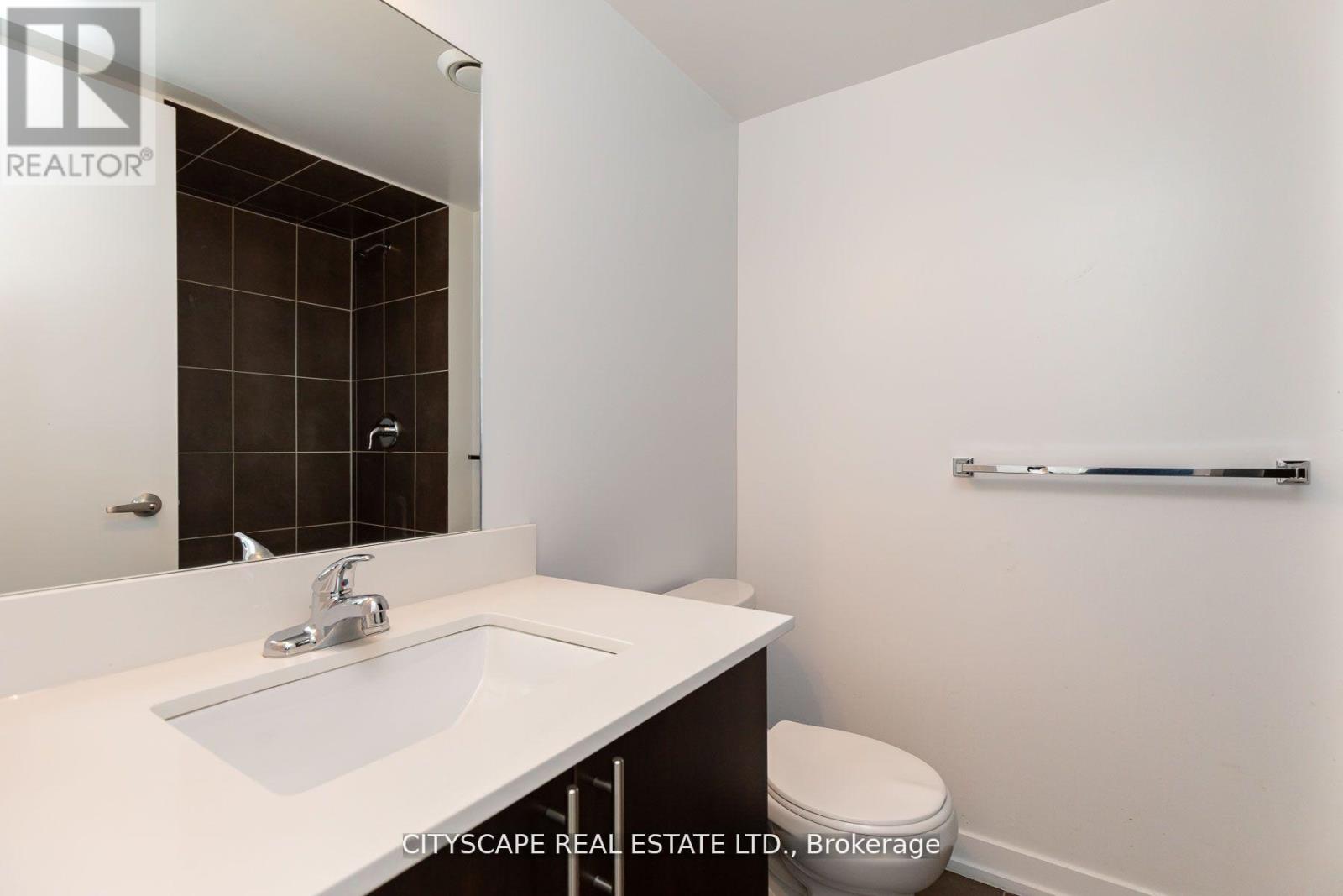 A bathroom with a sink, toilet and mirror.