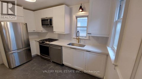 A kitchen with white cabinets and a stainless steel refrigerator.