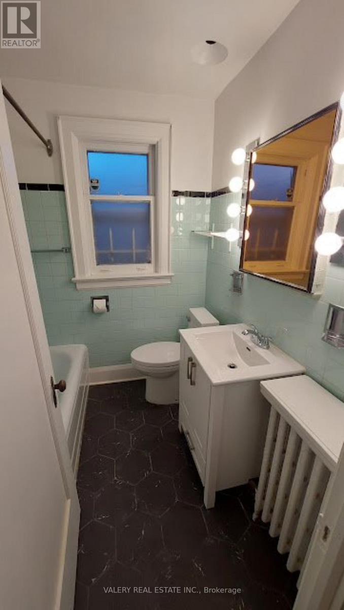 A bathroom with a toilet, sink, and mirror.
