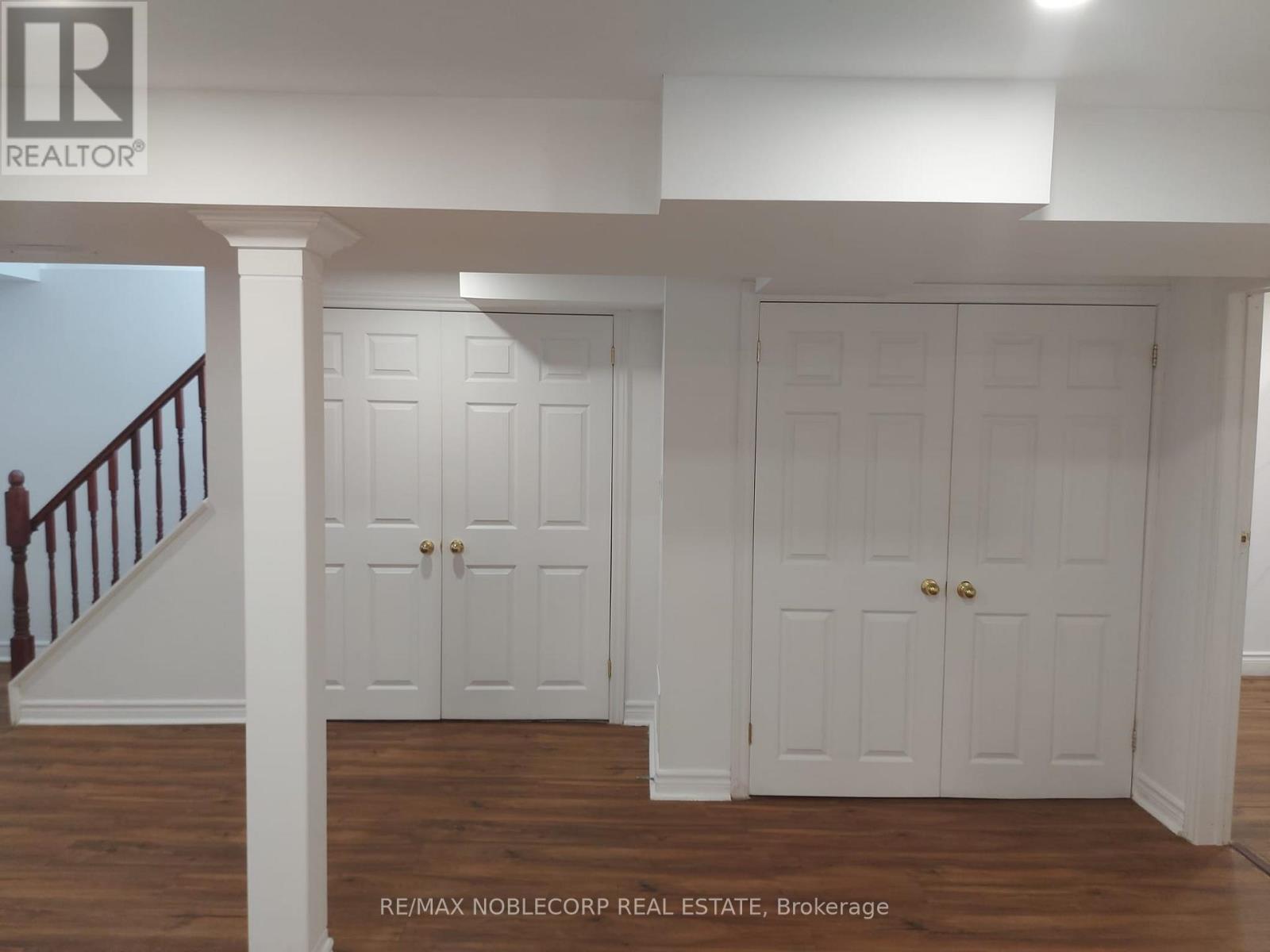 A white interior with a staircase on the left and two doors in the center.