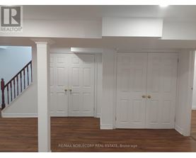 A white interior with a staircase on the left and two doors in the center.
