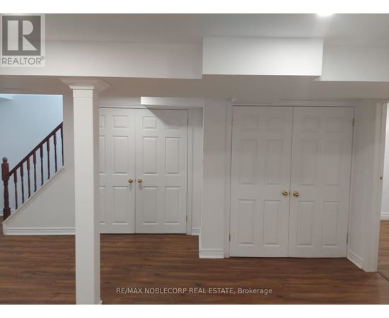 A white interior with a staircase on the left and two doors in the center.