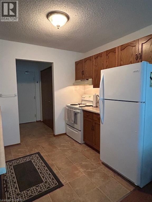 A kitchen with a white refrigerator and a washer and dryer unit.
