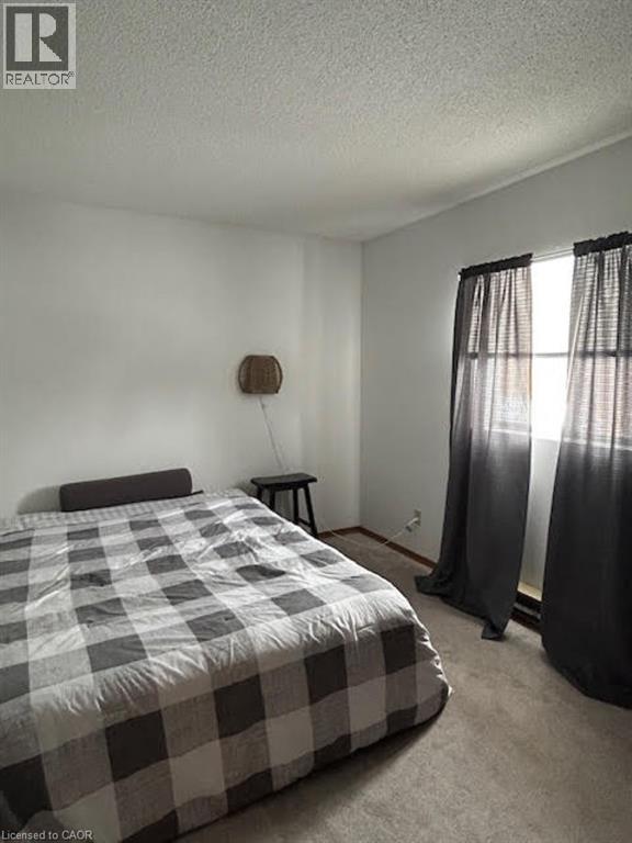 A bedroom with a bed, nightstand, and window with curtains.