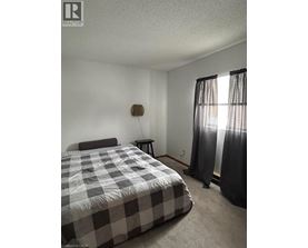 A bedroom with a bed, nightstand, and window with curtains.