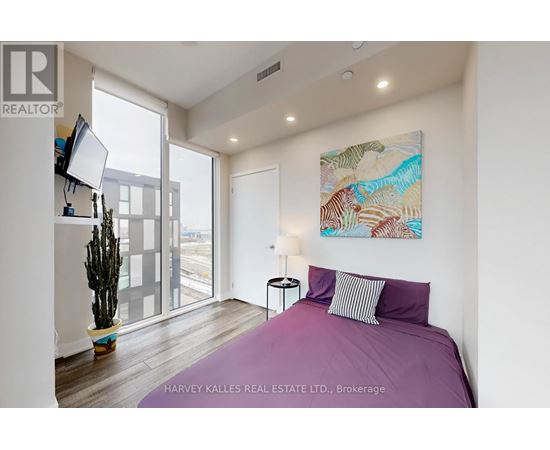 A bedroom with a purple bed and a painting on the wall.