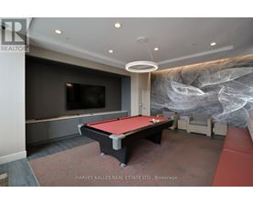 A pool table in a room with a television and a large painting on the wall.