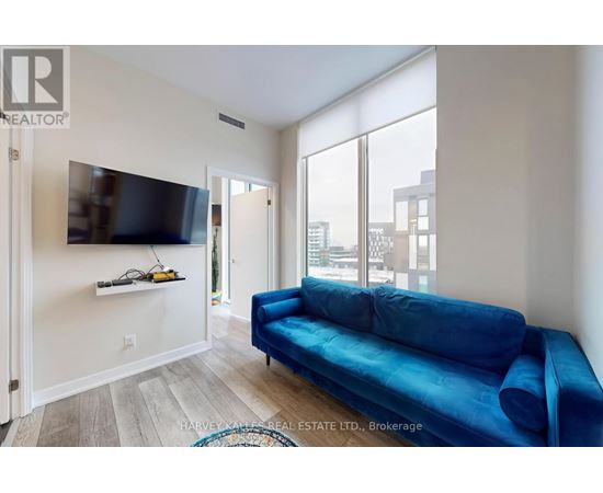 A living room with a blue couch and a flat screen TV mounted on the wall.