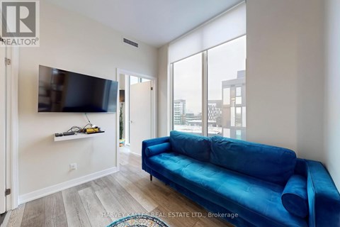 A living room with a blue couch and a flat screen TV mounted on the wall.