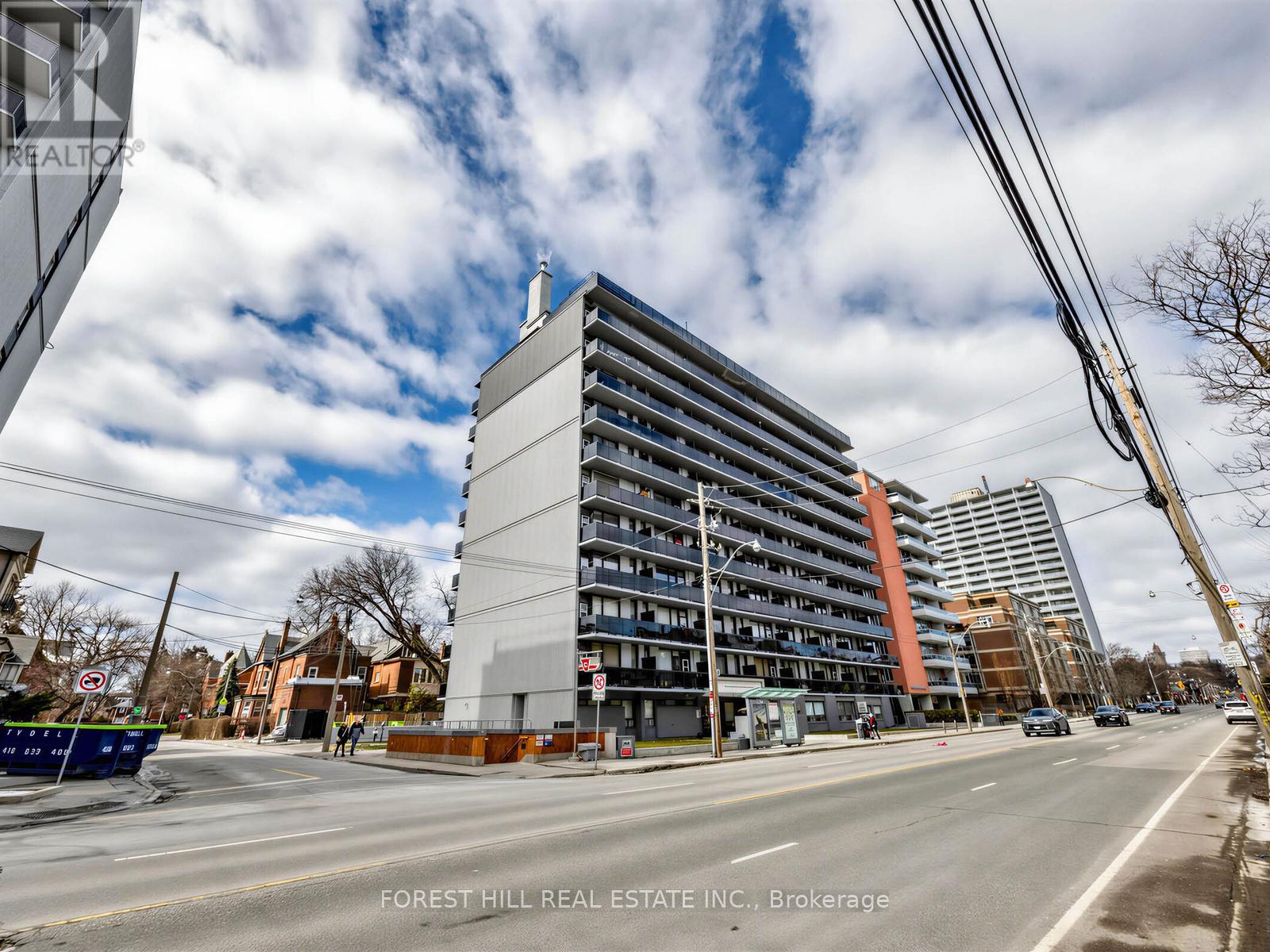 A street view of a multi-story building with cars parked on the side of the road.