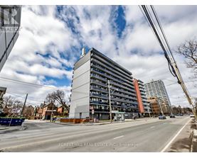 A street view of a multi-story building with cars parked on the side of the road.