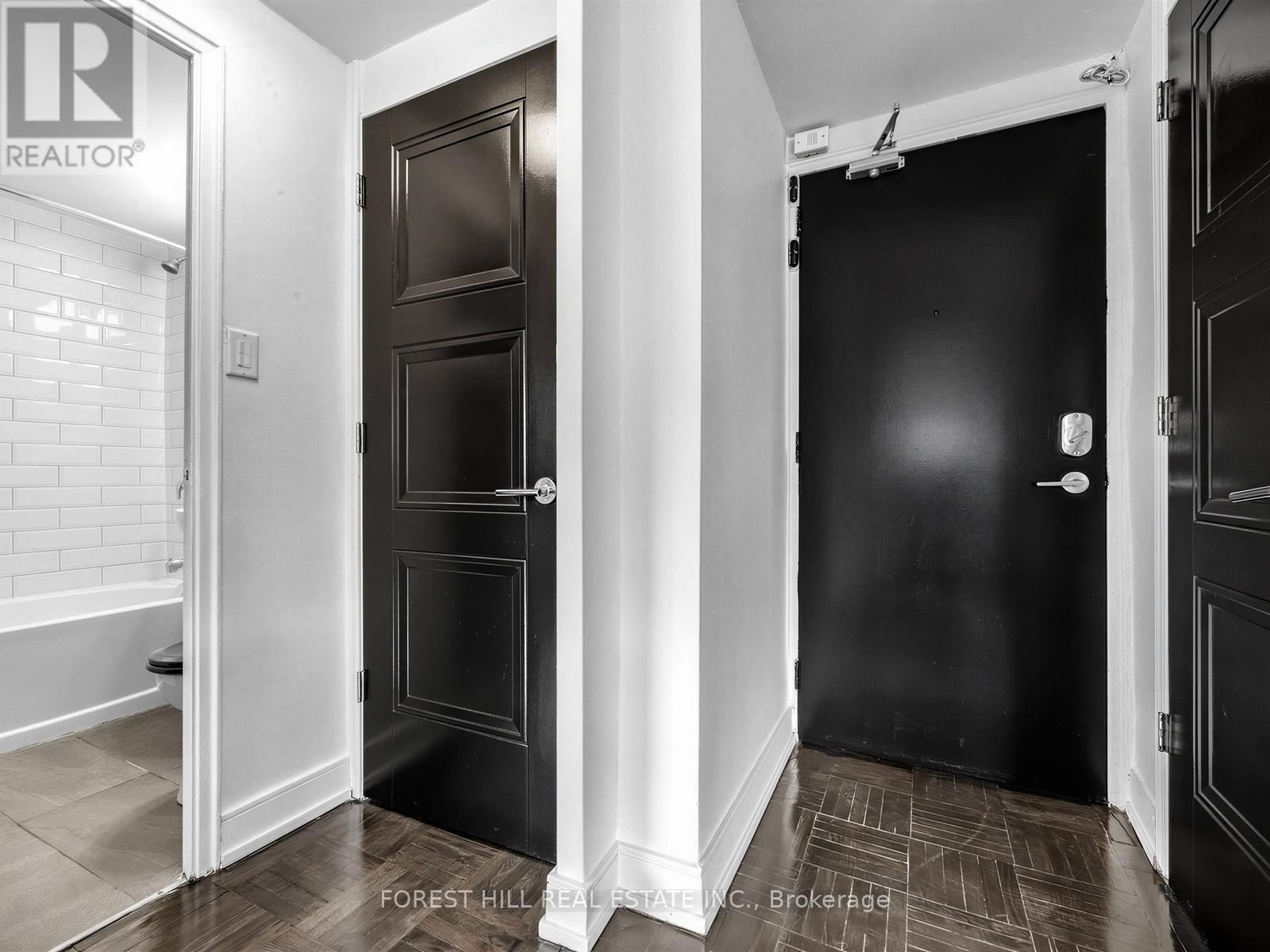A hallway with two doors and a brokerage sign on the wall.