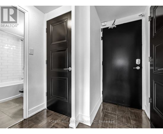 A hallway with two doors and a brokerage sign on the wall.
