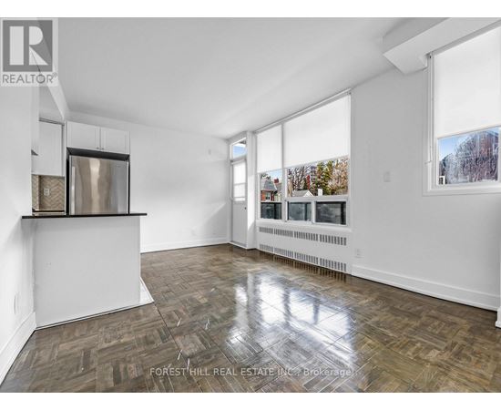 A spacious room with wooden flooring and large windows.