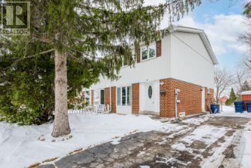 A house with a white and brown exterior is surrounded by snow.
