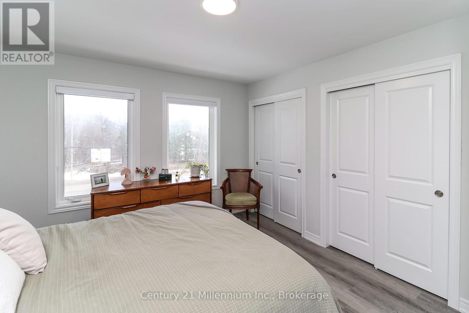 A bedroom with a bed, a chair, and a dresser with a mirror.