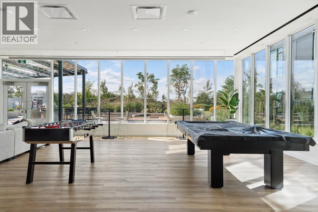 A room with a pool table and a view of the outdoors through the windows.
