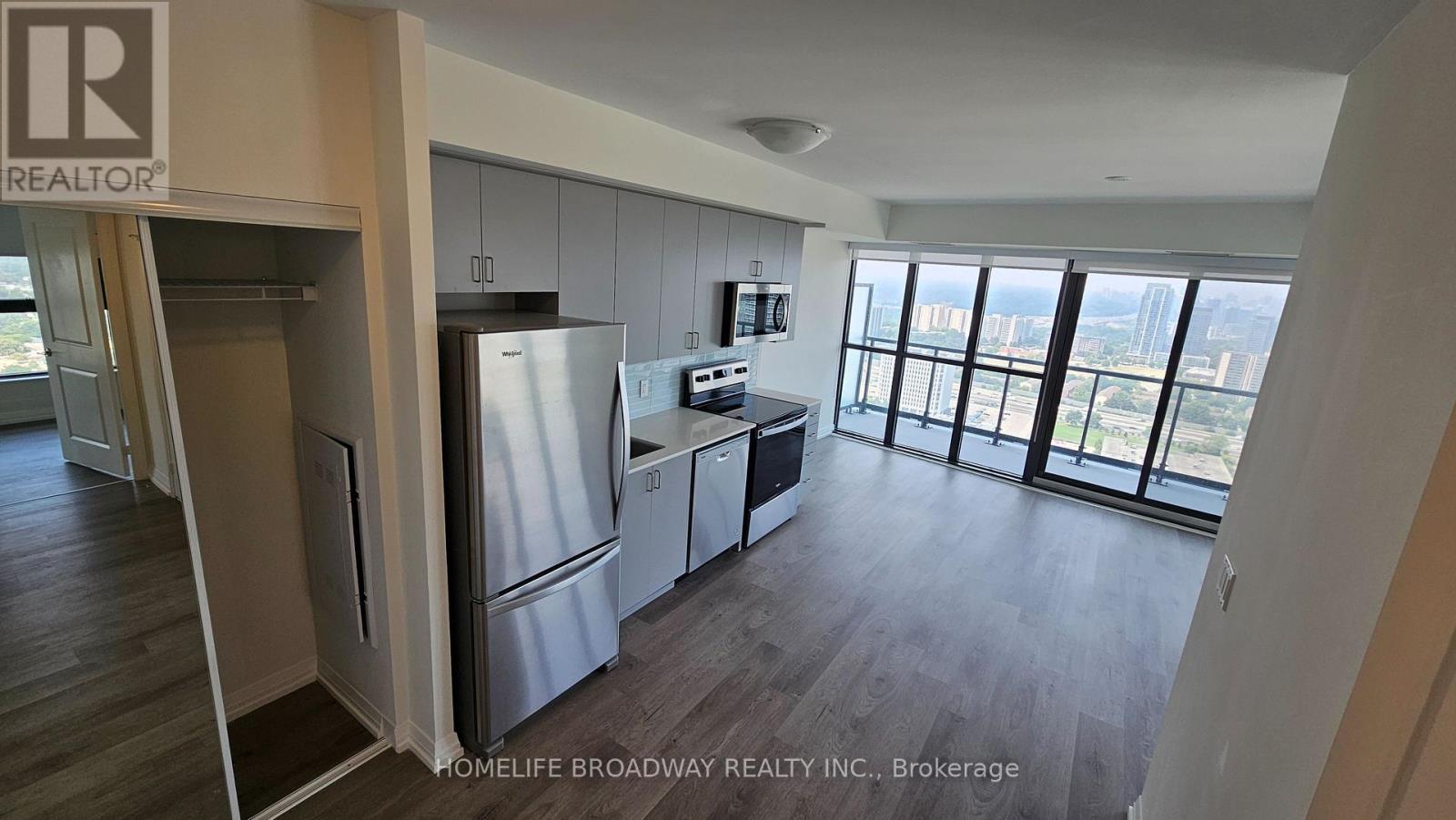 A kitchen with a refrigerator, cabinets, and a microwave.