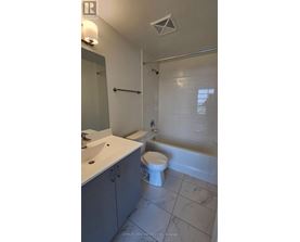 A white toilet sits in a bathroom next to a bathtub.