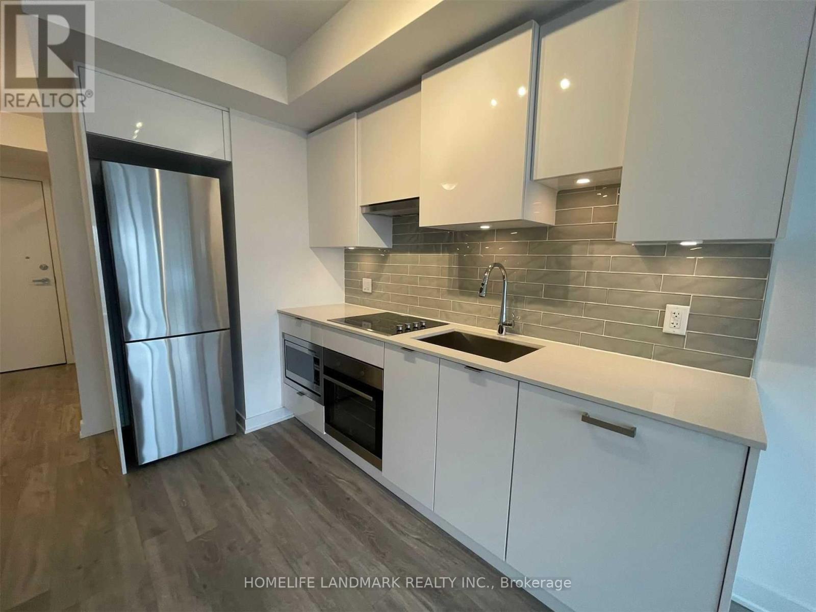 A kitchen with white cabinets and a grey backsplash.