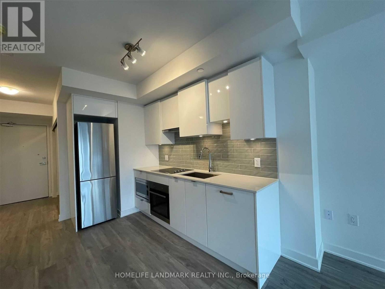 A modern kitchen with white cabinets and a wooden floor.