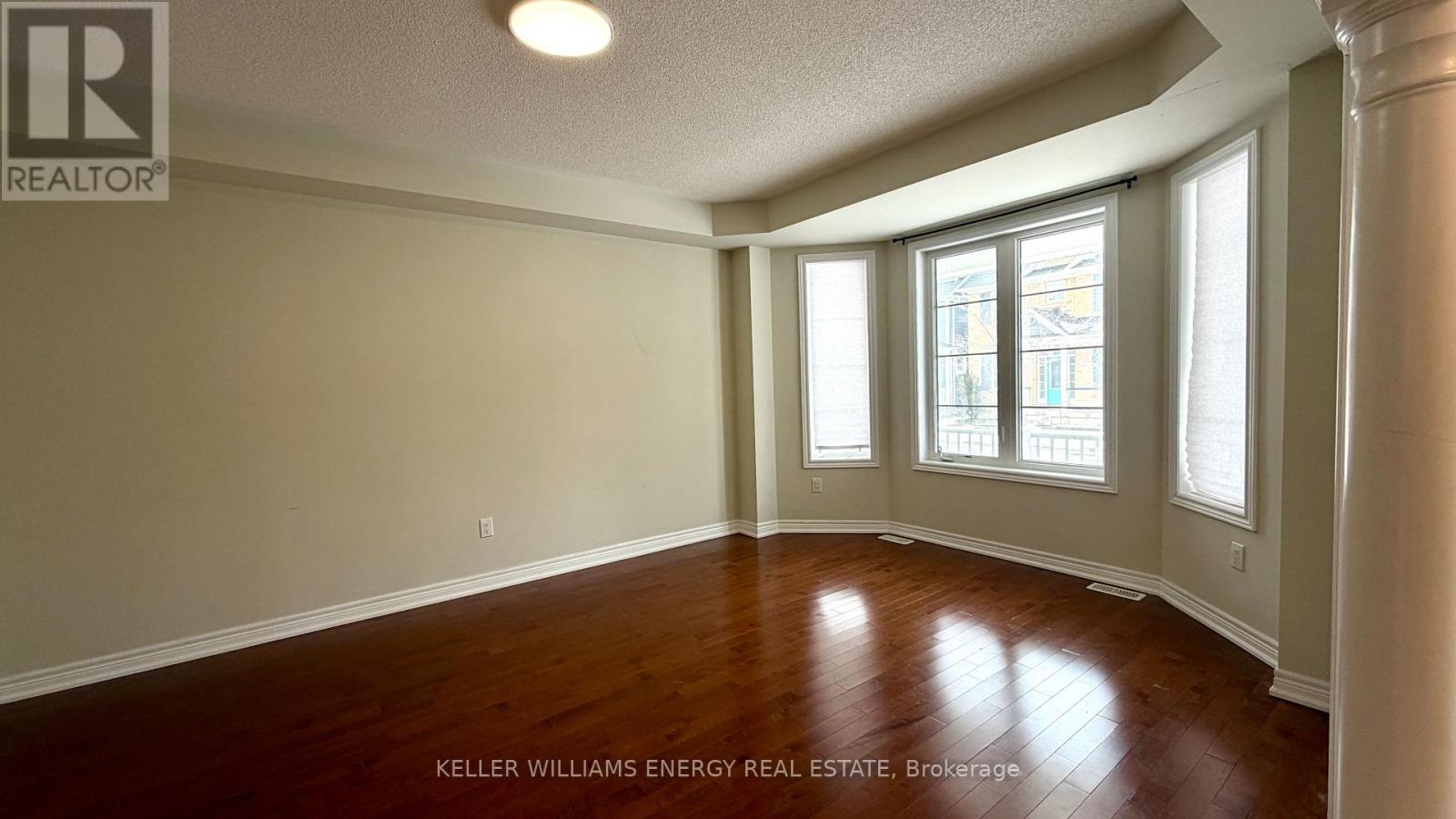 A room with wooden floors and a window with a view of a building outside.