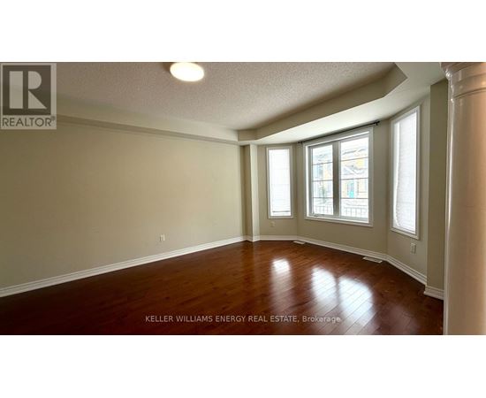 A room with wooden floors and a window with a view of a building outside.