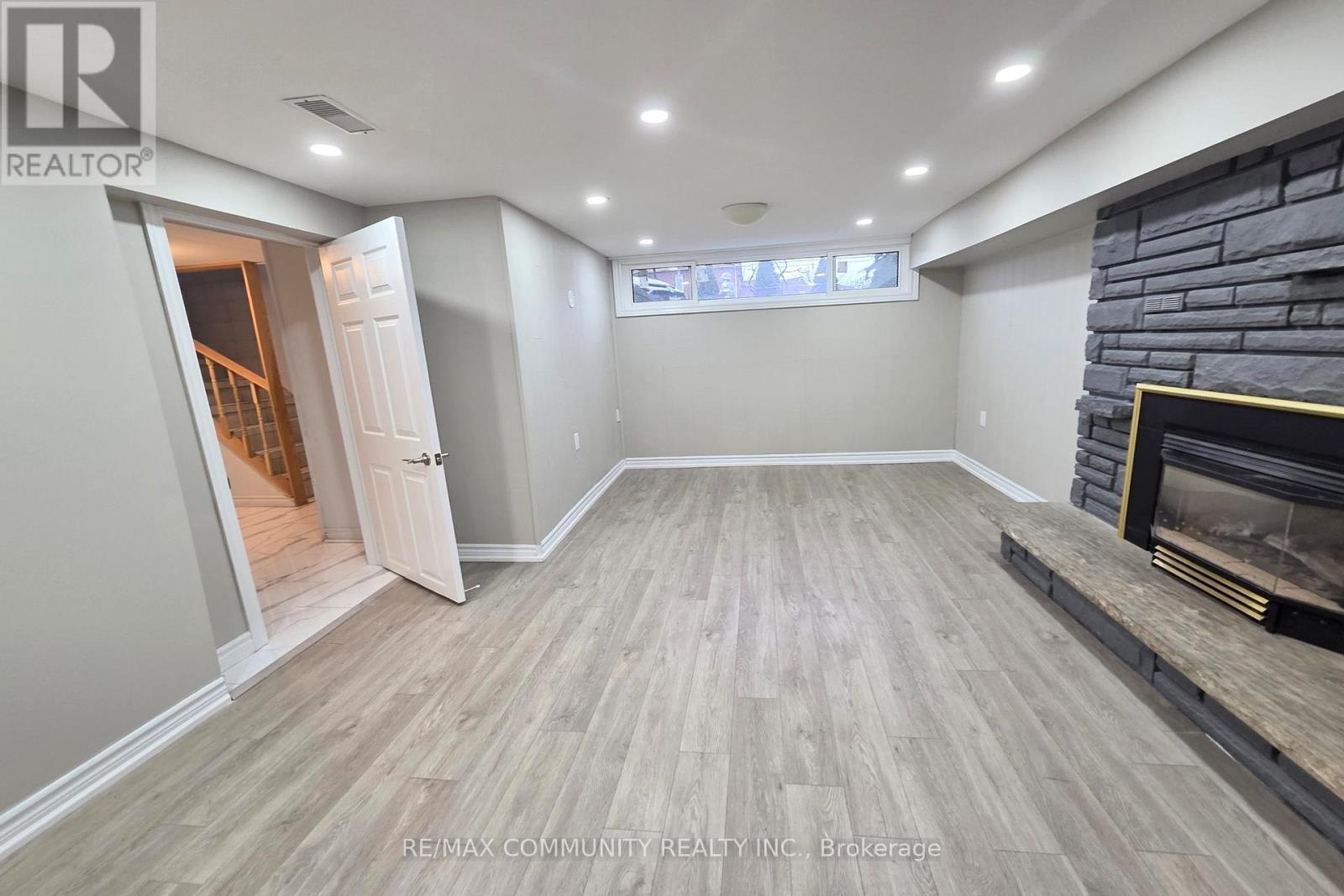 A spacious room with a fireplace and a doorway leading to another room.