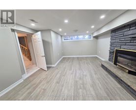 A spacious room with a fireplace and a doorway leading to another room.